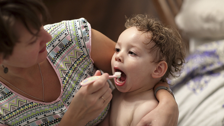 Mother brushing baby's teeth