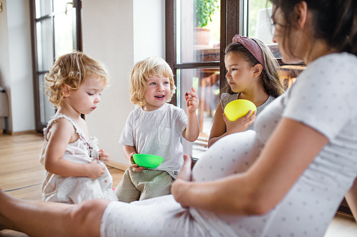 Pregnant woman with small children indoors at home