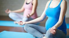 Pregnant women sitting in pose of lotus in gym