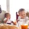 Young interracial family with little children having breakfast.