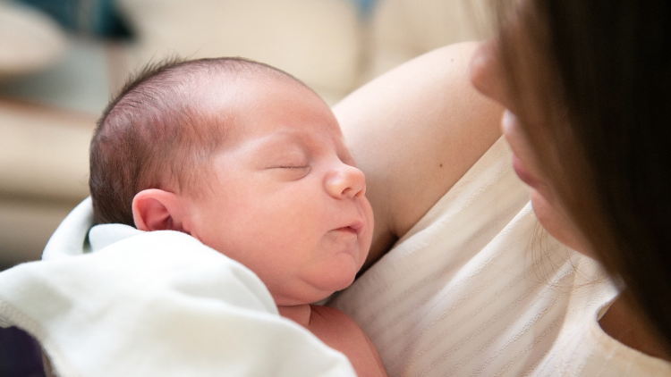 Image of mother cradling her newborn baby in her arms